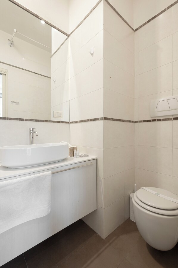 A bathroom with a white sink, mirror, and toilet.