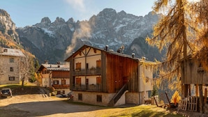 Ein rustikales Berglodge mit Holzfassade, einem Balkon und Blick auf schneebedeckte Berge.