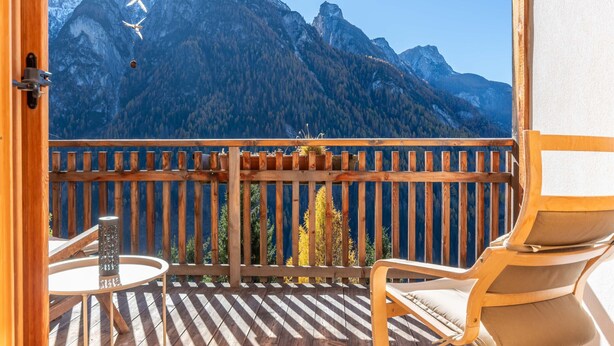 Ein Balkon mit Holzgeländer, einem Tisch und einer Dekoration sowie einem Stuhl.