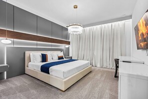Ein modernes Schlafzimmer mit einem großen Bett, einem Fernseher und einer Kandelaberleuchte.