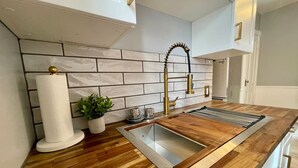 Una cocina moderna con encimera de madera, pileta integrada y salpicadero de azulejos blancos.