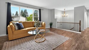 Un salon moderne avec un canapé, une table basse en verre et une vue sur l’extérieur.