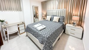 A modern bedroom with a large bed, bedside tables, a desk, and a mirror. - Beautiful apartment in Juan Dolio (Playa Juan Dolio)