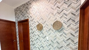 A hallway with a herringbone patterned wall, two wooden doors, and two woven wall hangings. - Beautiful apartment in Juan Dolio (Playa Juan Dolio)