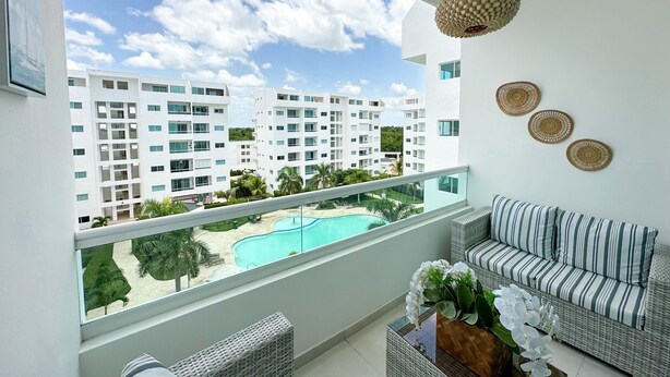 A balcony with a view of a swimming pool and adjacent buildings. - Beautiful apartment in Juan Dolio (Playa Juan Dolio)