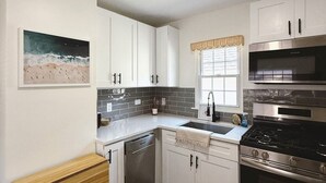 Una cocina moderna con armarios blancos, estufa de acero inoxidable y lavavajillas.