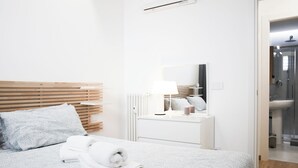 A hotel room with a bed, a bedside table with a lamp, a mirror, and a view of the bathroom. - Cozy Design Apartment in Milan | Piola/Center (Milano)