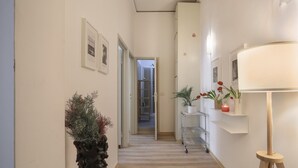 Ein Flur mit einem Blumentopf, einem roten Tablett, einer Lampe und einem Regal mit Dekoration.