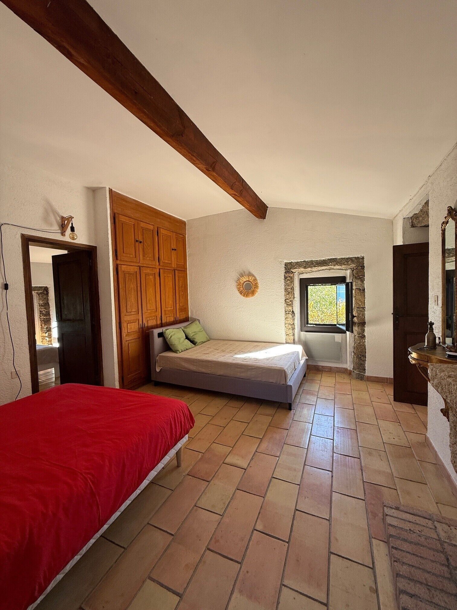 Ein Schlafzimmer mit Bett, Kleiderschrank, Steinwand und Fenster.