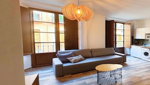A modern living room with a sofa, a round coffee table, and a hanging light fixture. - Apartamentos Plaza San Agustin 3000 (Granada)