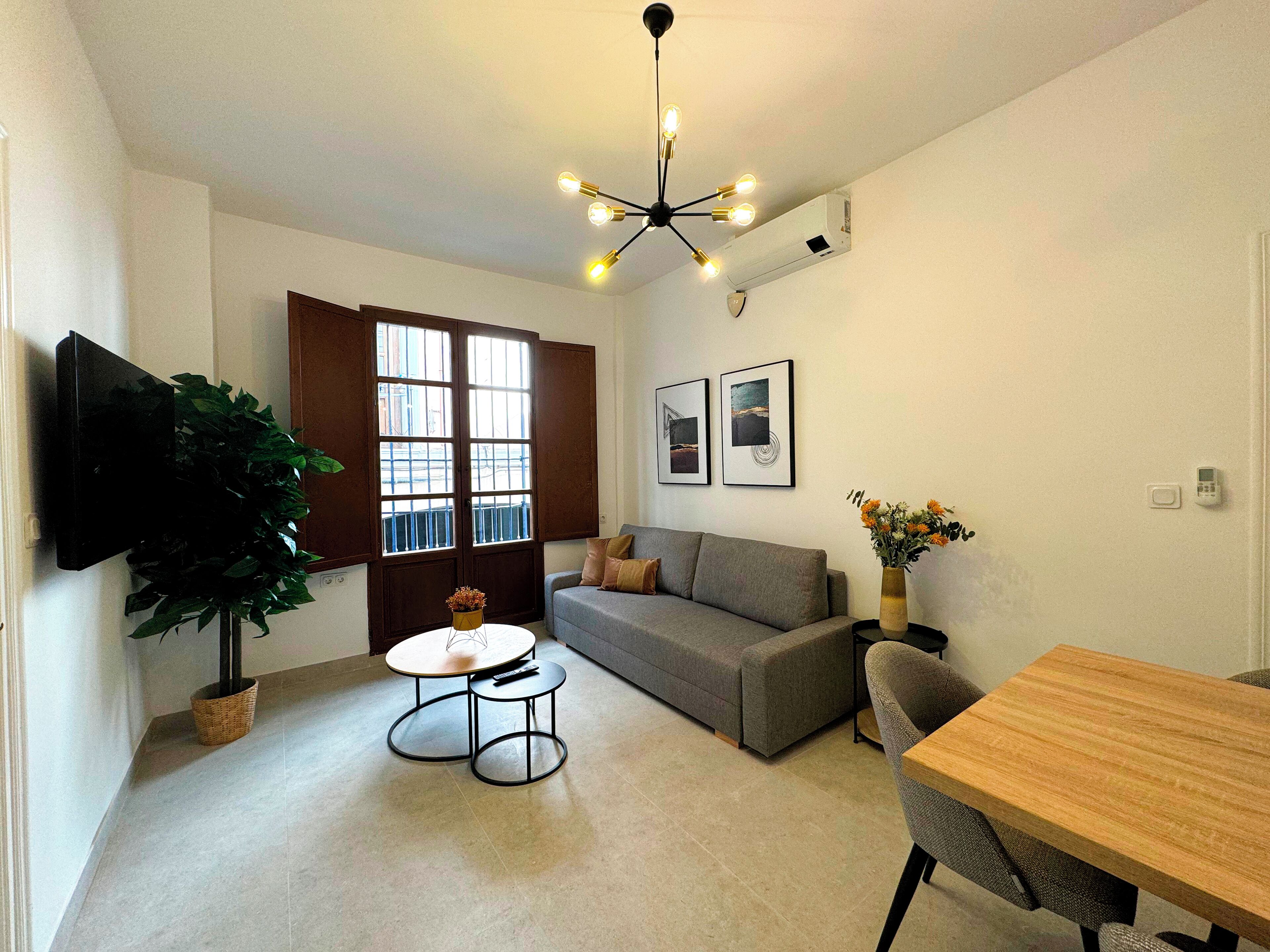 A modern living room with a sofa, a coffee table, a TV, and a dining table.