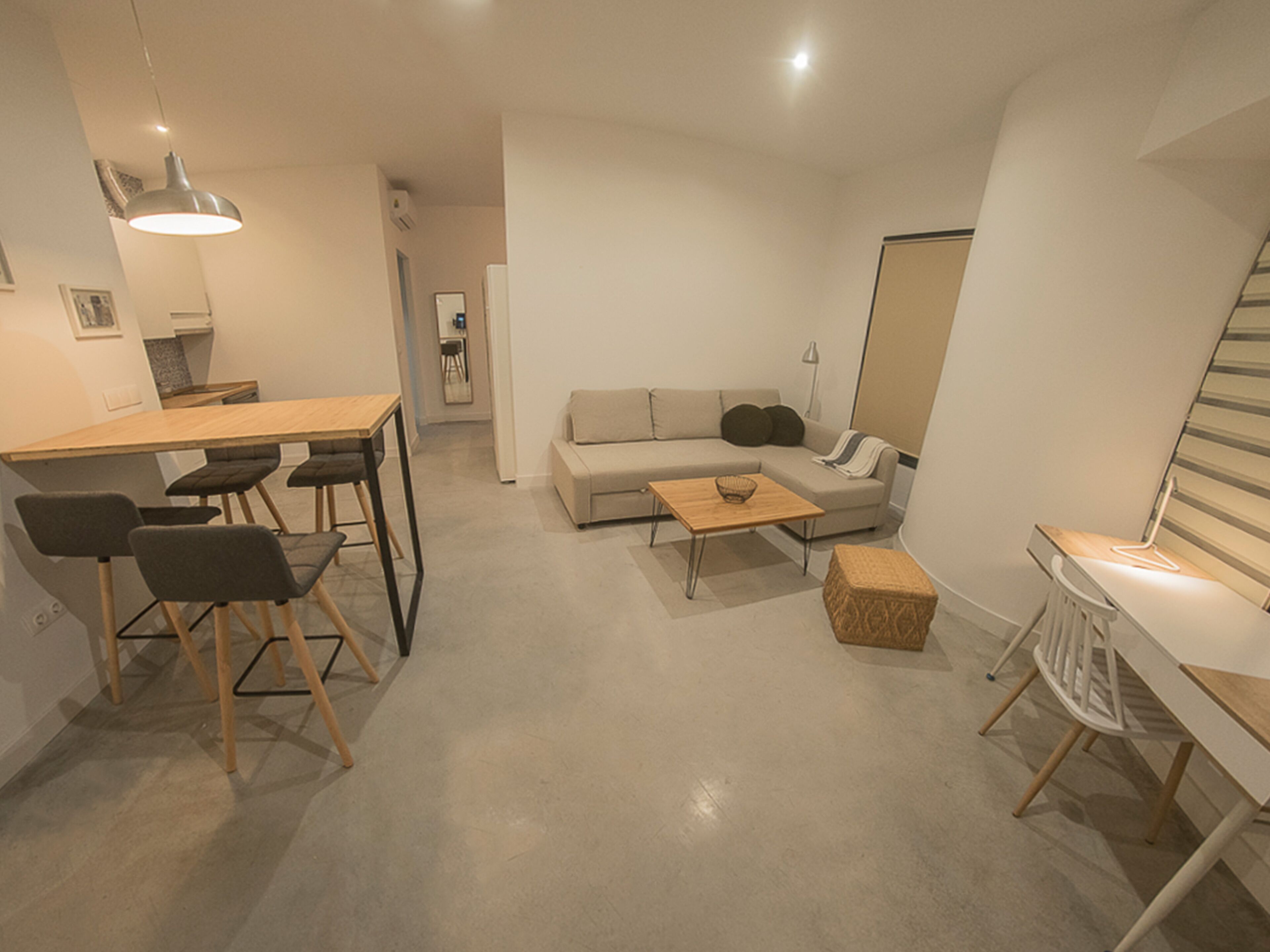 Ein moderner, minimalistischer Wohnraum mit Essbereich, einer Couch und einem kleinen Tisch.