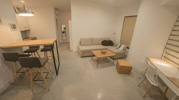 Ein moderner, minimalistischer Wohnraum mit Essbereich, einer Couch und einem kleinen Tisch.