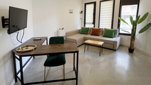 A modern living room with a sofa, a dining table, a TV, and a potted plant. - Apartamento Granada Parque Ciencias 3000 (Granada)