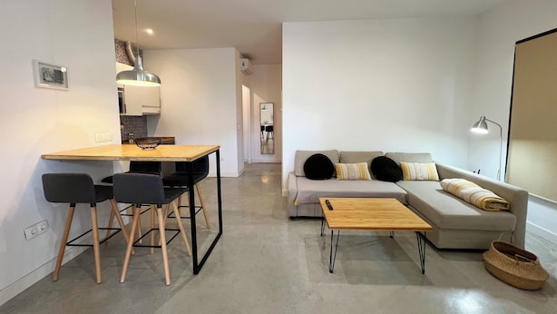 A modern living space with a dining area, a sofa, and a coffee table. - Apartamento Granada Parque Ciencias 3000 (Granada)