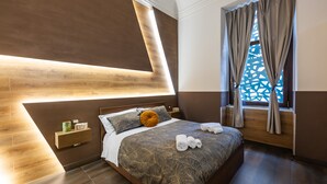 A modern bedroom with a wooden headboard, a large bed with a patterned bedspread, a bedside table with a lamp, and a window with curtains. - etna hill (Catania)
