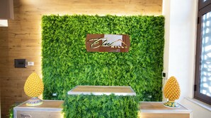 A reception desk with a green wall backdrop, a sign reading "Etw Hills", and two decorative pineapple sculptures. - etna hill (Catania)