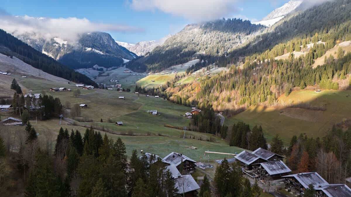 Un paysage montagneux parsemé de quelques petits bâtiments, probablement situé dans une zone rurale au milieu d’un environnement naturel.