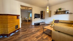 Una sala de estar con un sofá, una mesa de centro, un televisor y una chimenea.