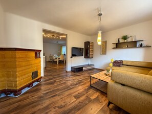A living room with a sofa, a coffee table, a TV, and a fireplace. - Apartment Leander with Mountain View, Private Terrace and Wi-Fi (Kleinsölk)
