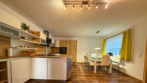Una cocina moderna con una isla central, suelo de madera y un comedor con vistas.
