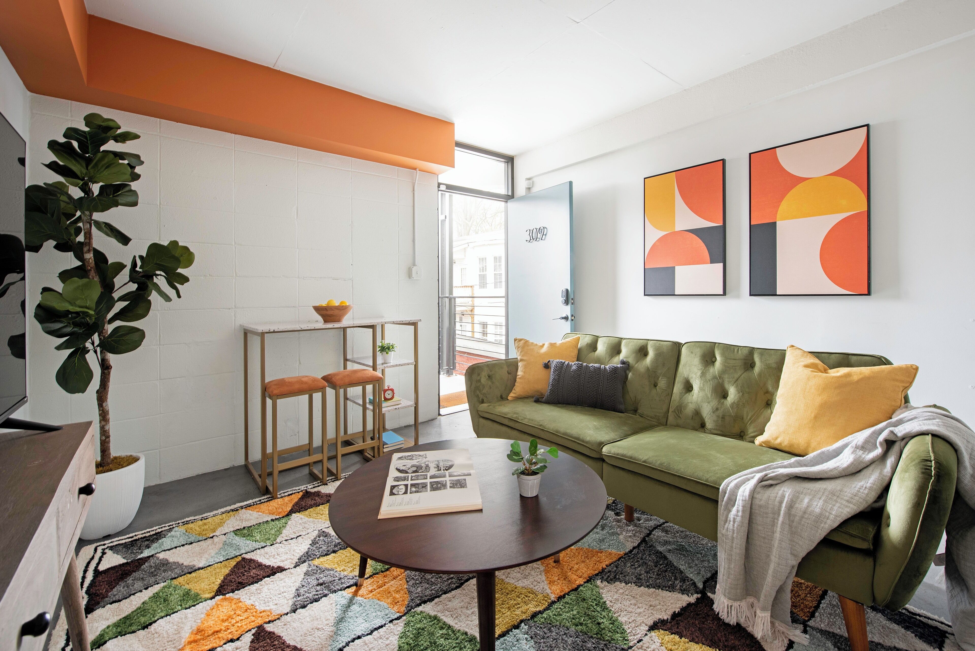 A modern living room with a green sofa, a coffee table, and a potted plant.