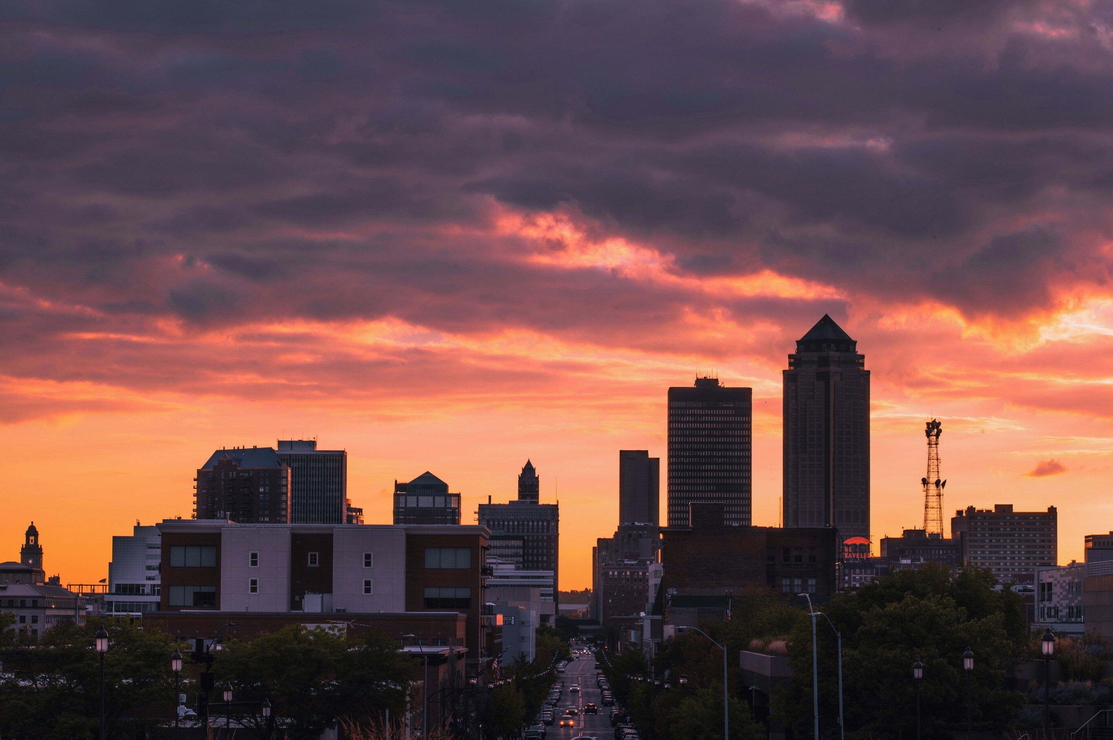 A city skyline at sunset with various buildings, including a prominent tower.