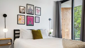 Un dormitorio moderno con una cama, mesitas de noche y una ventana con vistas a zonas verdes.
