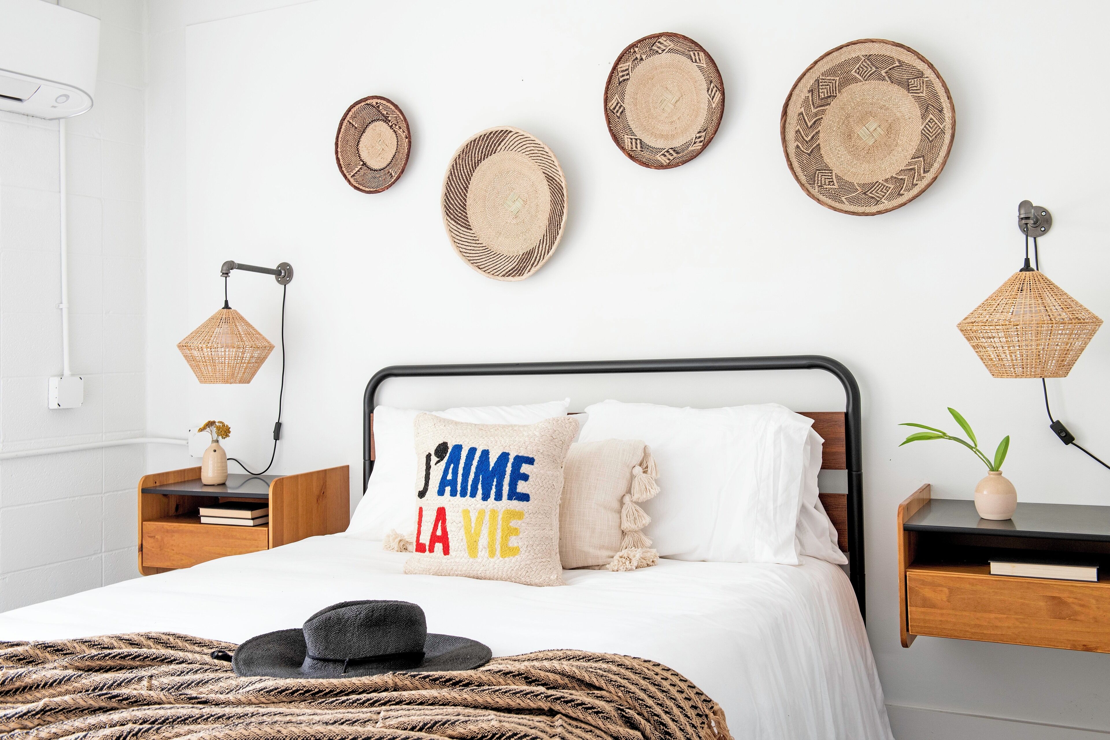 A bedroom with a bed, bedside tables, a wall-mounted lamp, and decorative plates.