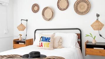 Ein Schlafzimmer mit einem Bett, Nachttischen, einer Wandlampe und dekorativen Tellern.