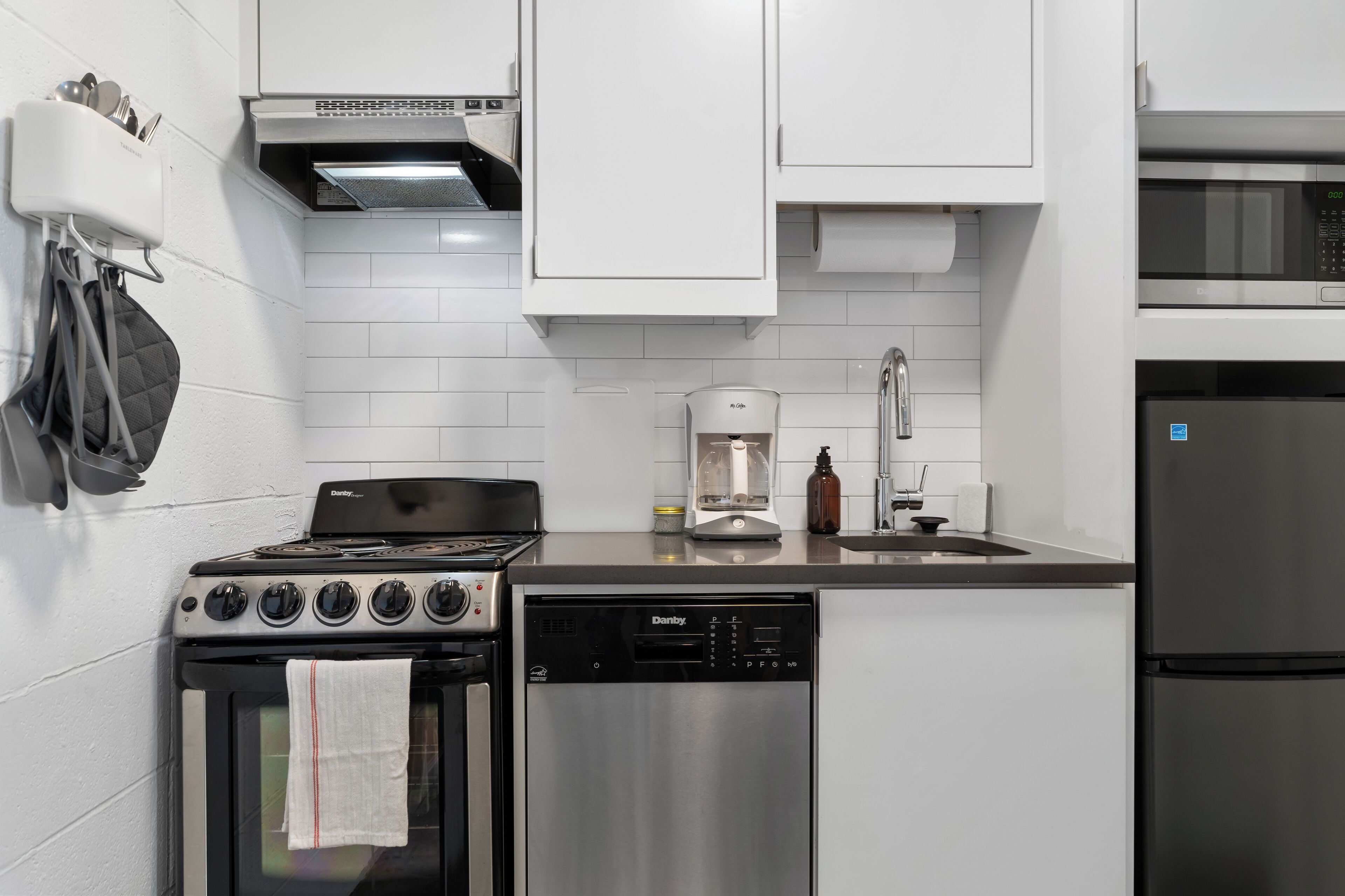 A modern kitchen with a stove, dishwasher, and refrigerator.