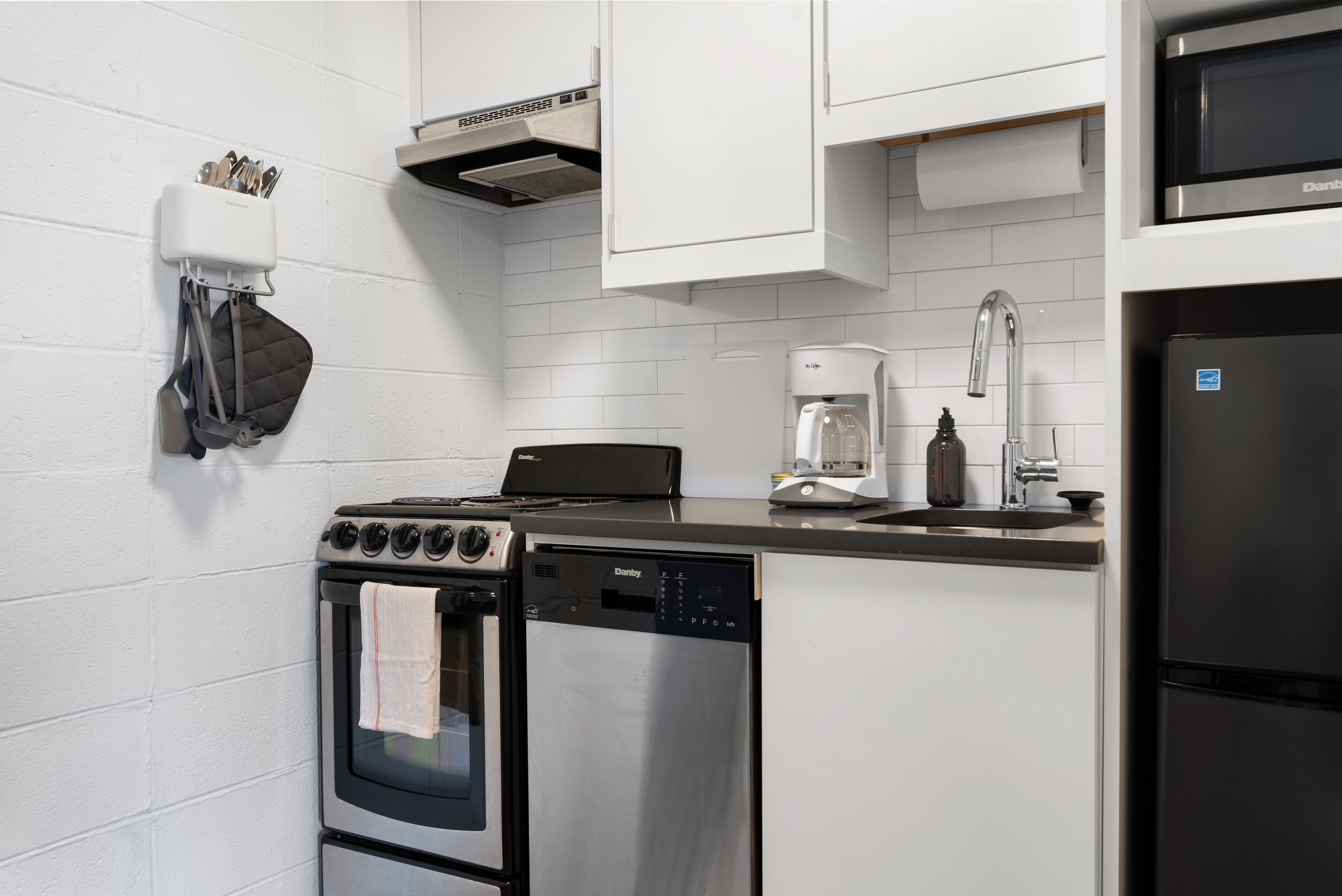 A kitchen with a stove, oven, dishwasher, coffee maker, and a refrigerator.