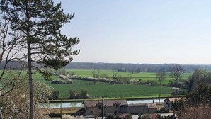 Un paisaje rural con un camino de grava, un edificio pequeño y campos al fondo.