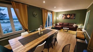 Una sala de estar moderna con una mesa de comedor de madera, sofá de cuero y vistas a una masa de agua a través de ventanas amplias.