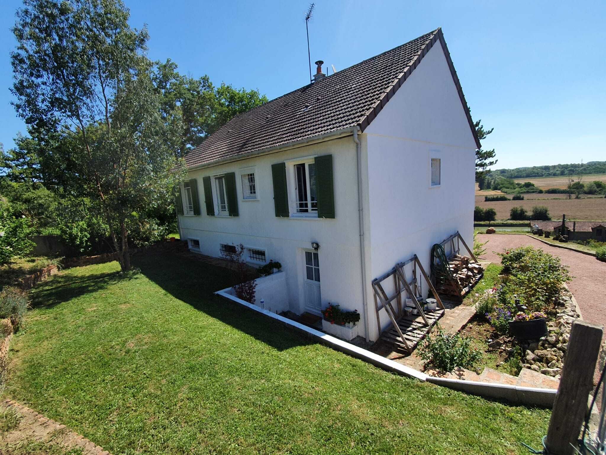 A white house with a sloped roof, green shutters, and a small front porch with steps.