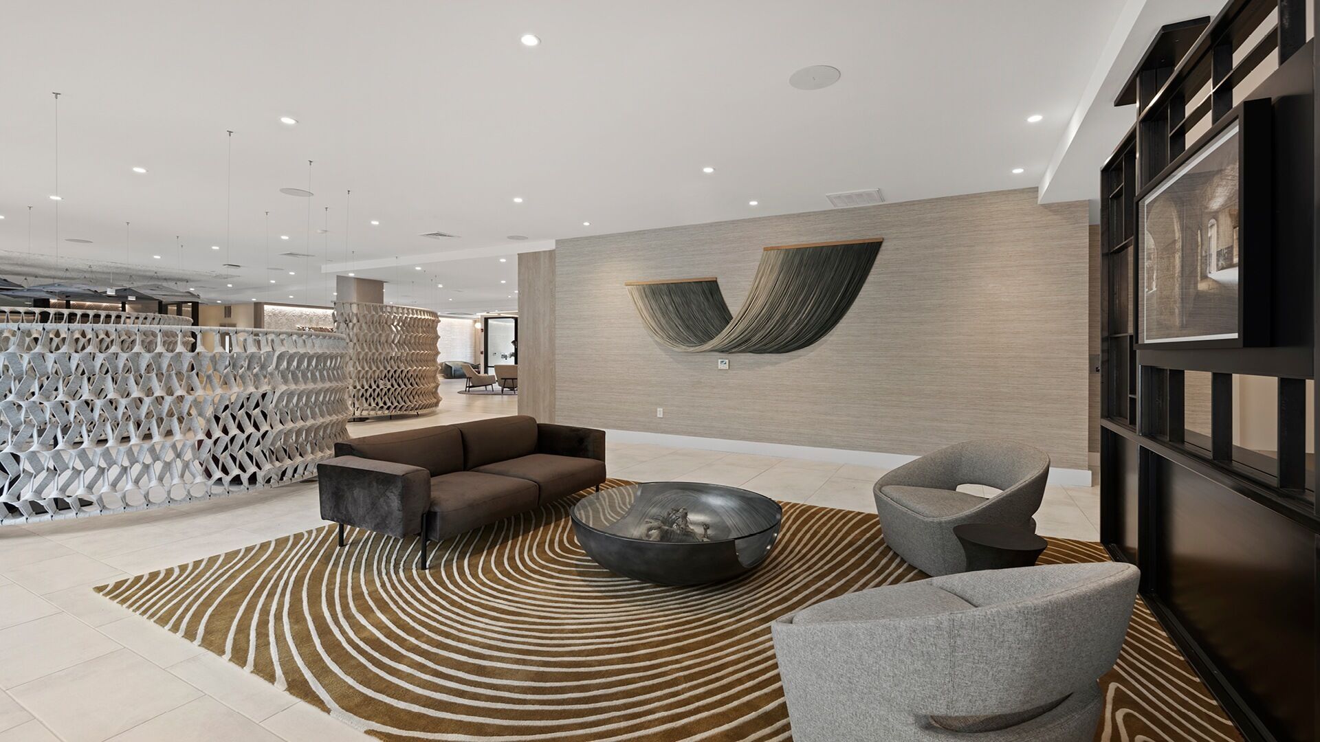 A modern lobby with a sectional sofa, a round coffee table, and a grey armchair.