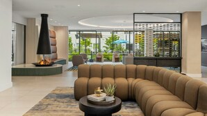 Een moderne woonkamer met een gebogen bank, een open haard en een presentatie van decoratieve objecten.