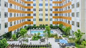 Een modern appartementencomplex met een centrale binnenplaats voorzien van een zwembad, buitenterras en groen.