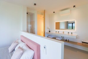 Ein modernes Badezimmer mit einem großen Spiegel, weißen Armaturen und Blick ins Freie.