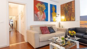 Ein Wohnzimmer mit einem beigen Sofa, einem Glastisch und zwei Bildern an der Wand.
