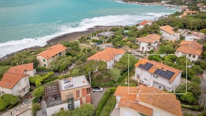 Eine Küstenwohngegend mit Häusern, einige davon mit Solaranlagen, und Blick aufs Meer.