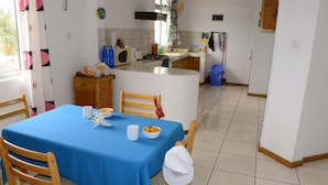 Ein Essbereich mit blauem Tischläufer, Holzstühlen und einem weißen Tisch, gedeckt mit Schüsseln und Tassen.