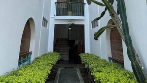 Un immeuble à plusieurs étages doté de balcons, d’une cour intérieure et d’un cactus au premier plan.