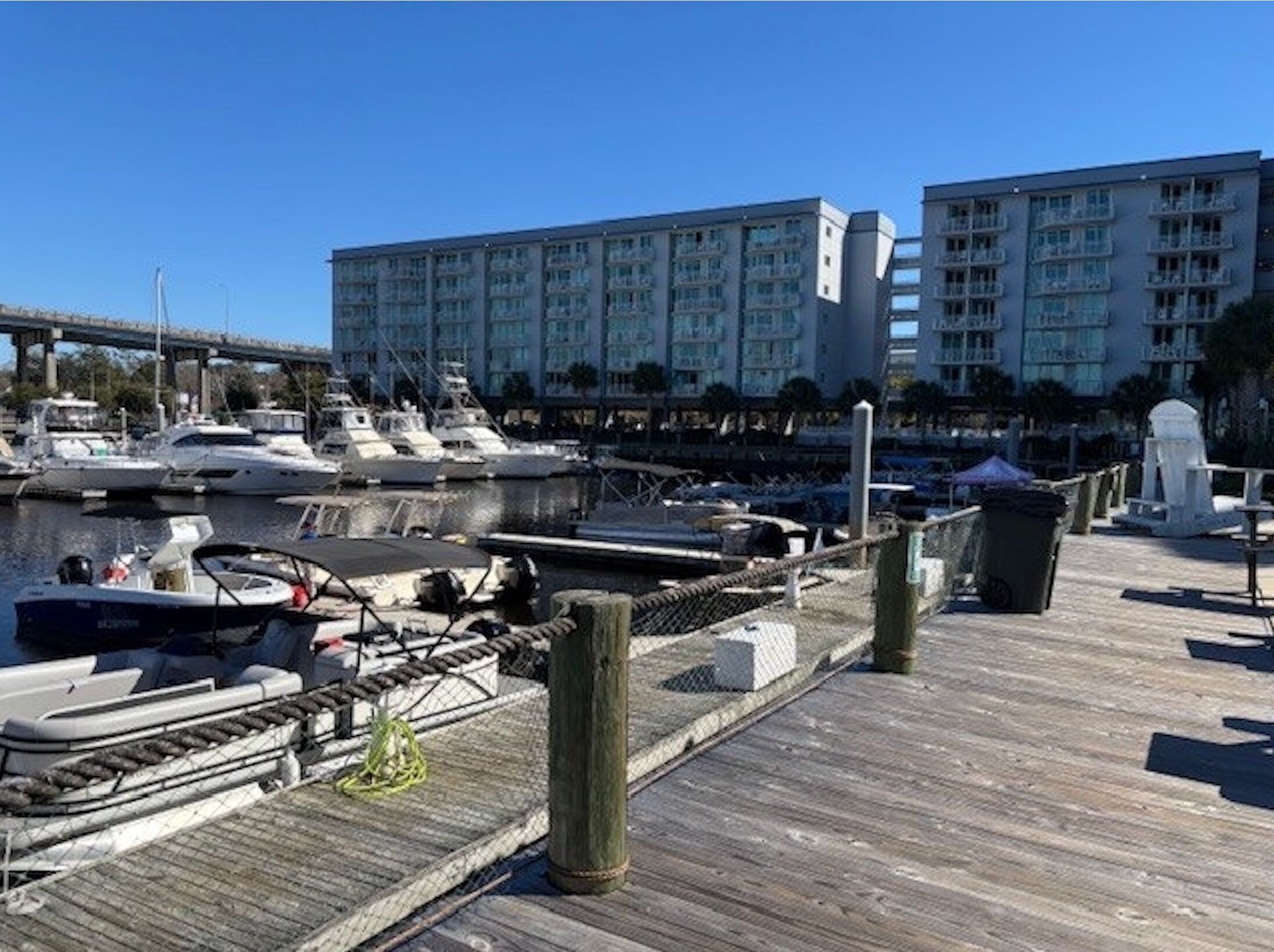 Un port de plaisance avec des bateaux amarrés, une jetée en bois et, au fond, un grand bâtiment d’hôtel.