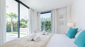 Moderni hotellihuone, jossa on suuri sänky, näkymä vehreälle maisemalle ja parveke.