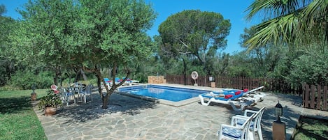 Una piscina con sillones de descanso y un patio de piedra.