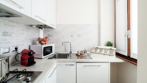 Una cocina compacta con gabinetes blancos, un microondas, una estufa a gas y un lavaplatos.