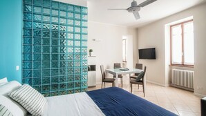 Una habitación de hotel con cama, escritorio, sillas, televisión y ventana.