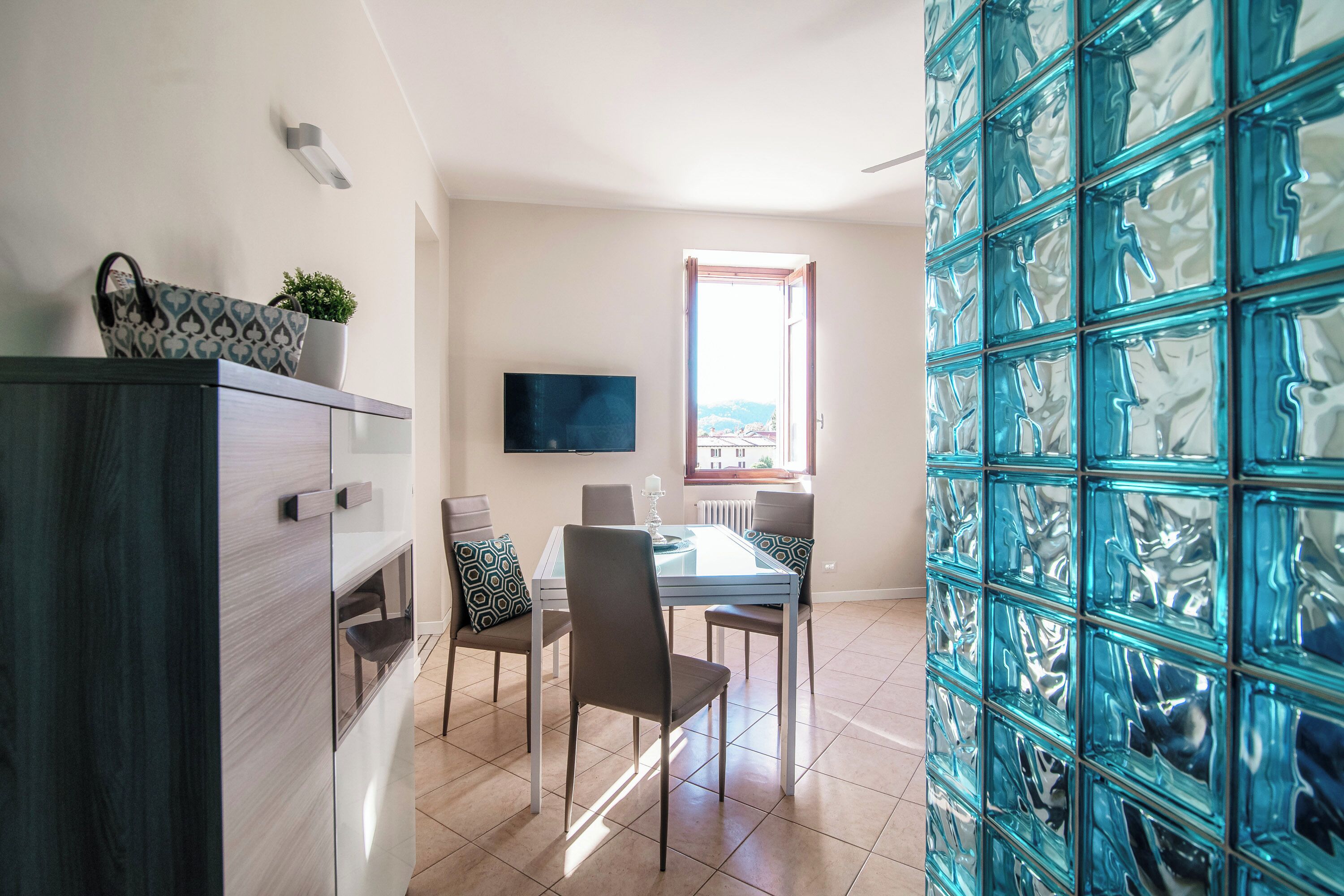 A dining area with a table, chairs, and a TV on the wall.