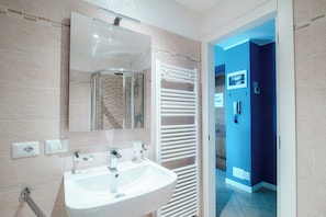 A modern bathroom with a white sink, a glass shower enclosure, and a towel rack. - Cigni (Cernobbio)